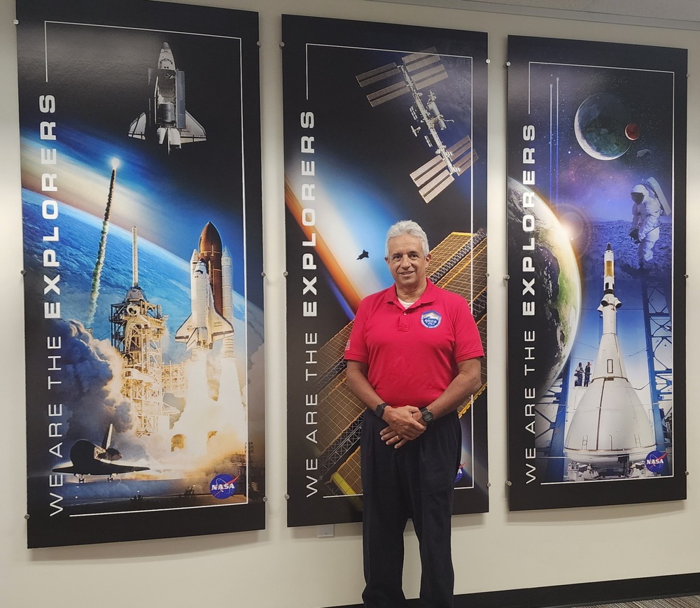 A person in a red shirt standing in front of three posters about space exploration.